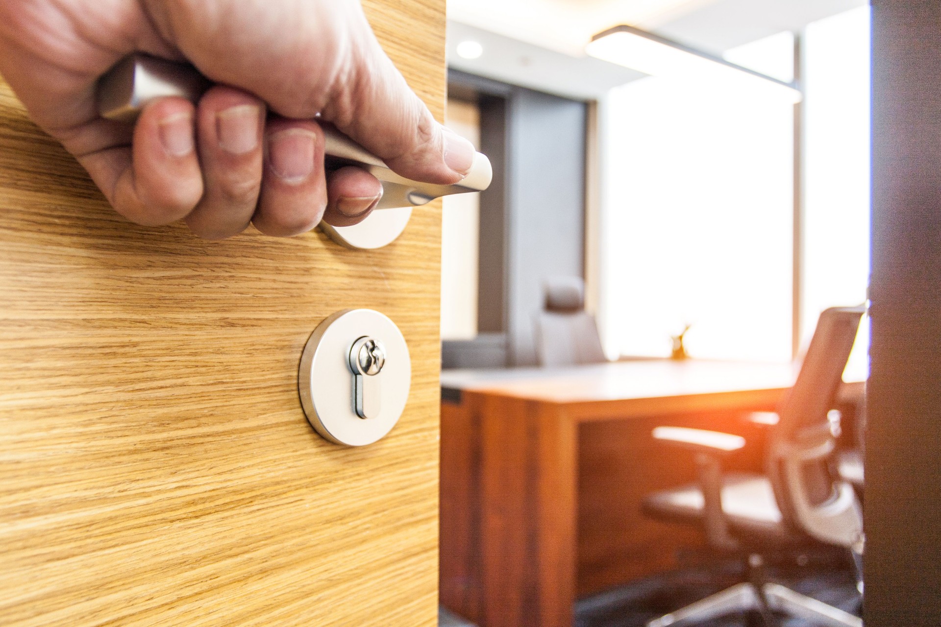 Hand pushing open the wooden door of the office